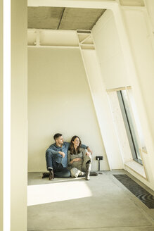 happy couple, expecting baby, sittig on floor of their new apartment - MJRF00194