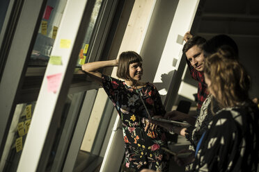 Colleagues brainstorming in office, standing at the window - MJRF00205