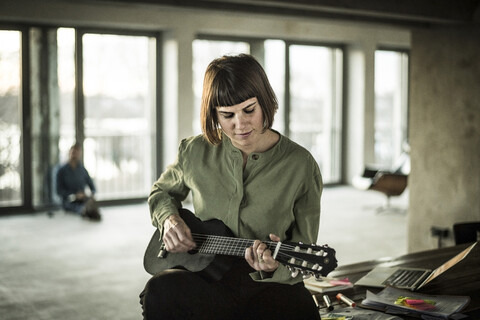 Geschäftsfrau spielt im Büro auf der Ukulele, lizenzfreies Stockfoto