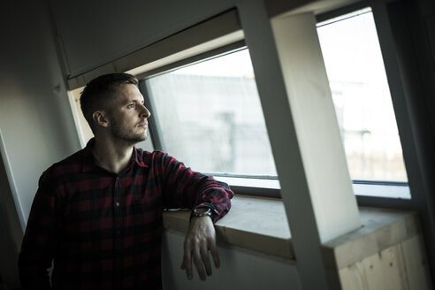 Young man looking out of window, daydreaming - MJRF00211