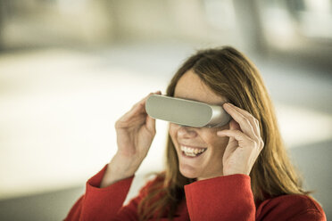 Smiling businesswoman looking through VR goggles - MJRF00221