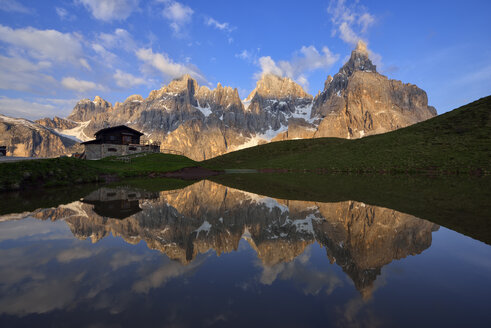 Italien, Trentino, Dolomiten, Passo Rolle, Gebirgskette Pale di San Martino, Cimon della Pala mit Baita Segantini, die sich in einem kleinen See am Abend spiegelt - RUEF02123