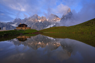 Italien, Trentino, Dolomiten, Passo Rolle, Gebirgskette Pale di San Martino, Cimon della Pala mit Baita Segantini, die sich in einem kleinen See am Abend spiegelt - RUEF02131