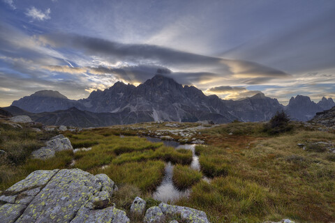 Italien, Dolomiten, Passo Rolle, Trentino, Pale di San Martino Berggruppe mit Berggipfel Cimon della Pala mit kleinem Teich bei Sonnenaufgang, lizenzfreies Stockfoto