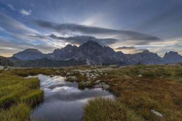 Italy, Dolomites, Passo Rolle, Trentino, Pale di San Martino Mountain group with mountain peak Cimon della Pala with small pond at sunrise - RUEF02166