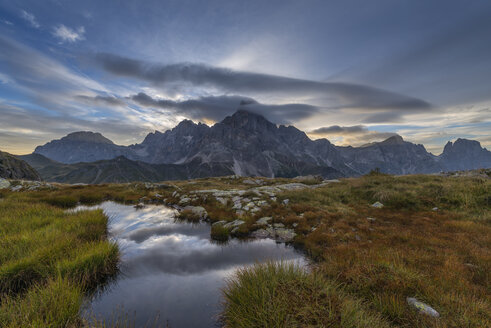 Italien, Dolomiten, Passo Rolle, Trentino, Pale di San Martino Berggruppe mit Berggipfel Cimon della Pala mit kleinem Teich bei Sonnenaufgang - RUEF02166