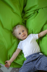 Portrait of little girl lying on green blanket in children's room - GAF00136