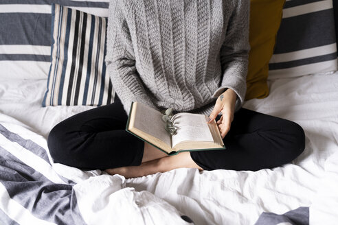 Frau sitzt auf dem Bett und liest ein Buch - FMOF00552