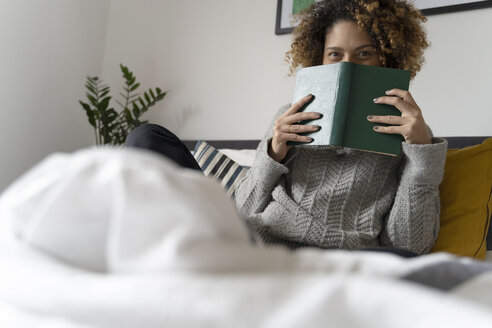 Frau sitzt auf dem Bett und liest ein Buch - FMOF00554