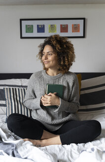 Frau sitzt auf dem Bett und liest ein Buch - FMOF00558