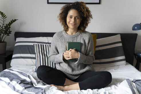 Frau sitzt auf dem Bett und liest ein Buch - FMOF00559