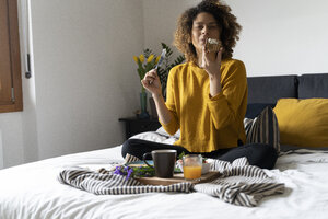 Frau, die auf dem Bett sitzt und ein gesundes Frühstück zu sich nimmt - FMOF00569