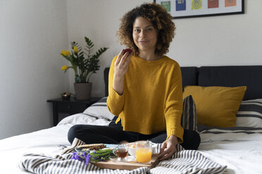 Frau, die auf dem Bett sitzt und ein gesundes Frühstück zu sich nimmt - FMOF00575