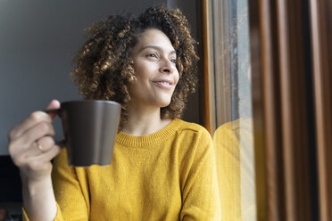 Woman sitting at window, taking a break, drinking coffee - FMOF00580