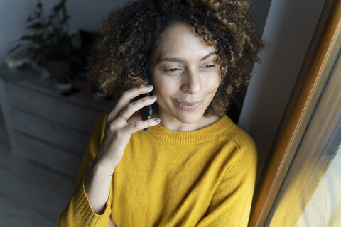 Frau telefoniert, schaut aus dem Fenster, lizenzfreies Stockfoto