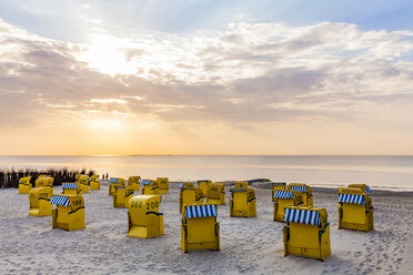 Germany, Lower Saxony, Cuxhaven, Duhnen, beach with hooded beach chairs at sunrise - WDF05242