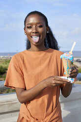 Portrait of young woman with lightblue icecream scoop showing tongue - VEGF00012