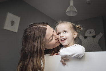 Mutter küsst glückliche Tochter im Kinderzimmer - KMKF00847