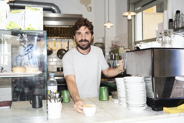 Portrait of smiling barista at the counter of a coffee shop - IGGF01153