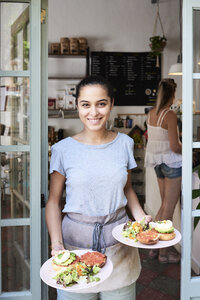 Porträt einer lächelnden Kellnerin, die das Frühstück serviert - IGGF01155