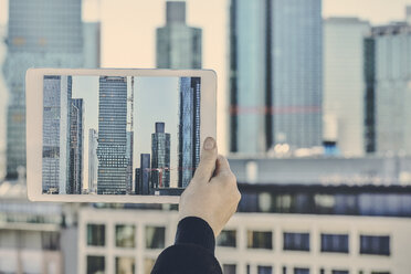 Germany, Frankfurt, hand taking photo of financial district with tablet - FMKF05538