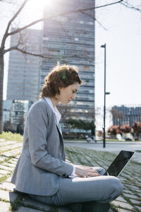 Geschäftsfrau in der Stadt, auf dem Boden sitzend, am Laptop arbeitend - JRFF03027