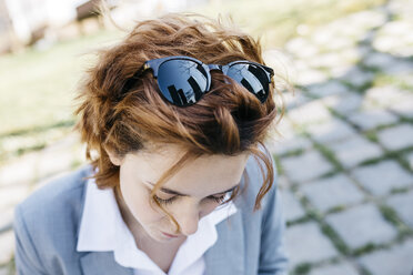 Junge Geschäftsfrau blickt nach unten, mit Spiegelung von Hochhäusern in ihrer Sonnenbrille - JRFF03032