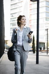Businesswoman with smartphone, commuting in the city - JRFF03055