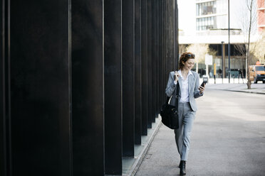 Businesswoman with smartphone, commuting in the city - JRFF03056