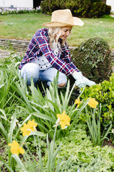 Young woman with a straw hat weeding weeds - HMEF00288