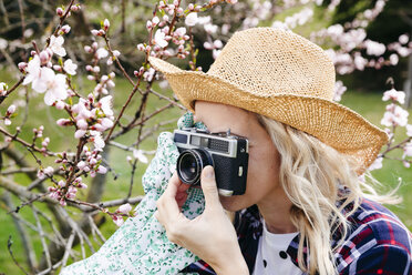 Junge Frau mit Strohhut fotografiert im Garten mit einer alten Kamera - HMEF00305