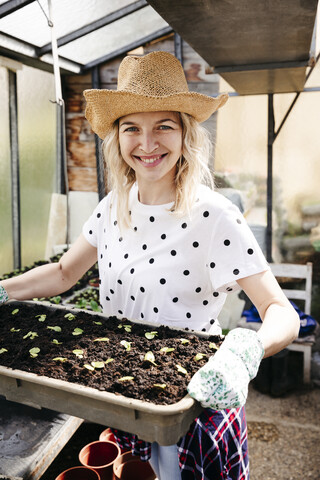 Junge Frau bei der Gartenarbeit in einem Gewächshaus, lizenzfreies Stockfoto