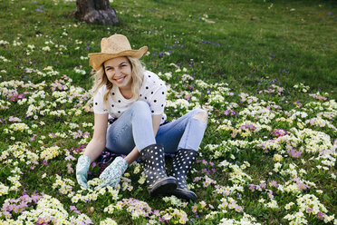 Junge Frau sitzt auf einer Blumenwiese - HMEF00327