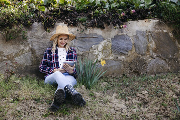 Young woman with straw hat working outdoor with her tablet - HMEF00333