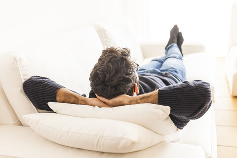 Back view of young man relaxing on couch at home stock photo