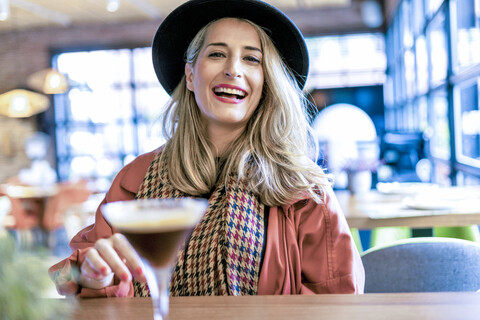Porträt einer glücklichen Frau mit einem Kaffeecocktail in einem Cafe, lizenzfreies Stockfoto