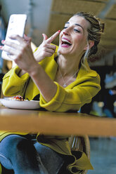 Happy playful woman taking a selfie in a cafe - ERRF01107