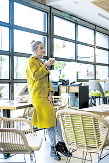 Frau trinkt Kaffee am Fenster eines Cafés - ERRF01109