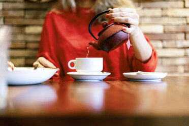 Nahaufnahme einer Frau, die in einem Café Tee in eine Tasse gießt - ERRF01111
