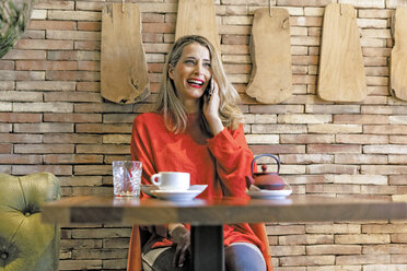 Lachende Frau am Mobiltelefon in einem Cafe - ERRF01116