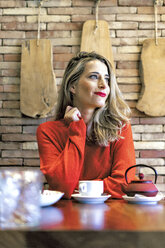 Smiling woman sitting at table in a cafe - ERRF01142