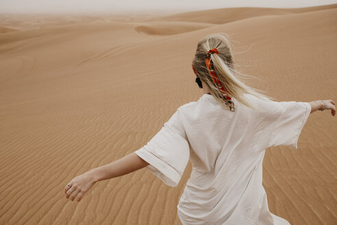 Vereinigte Arabische Emirate, Dubai, Wüste Lahbab, Frau geht in Wüstenlandschaft - LHPF00529