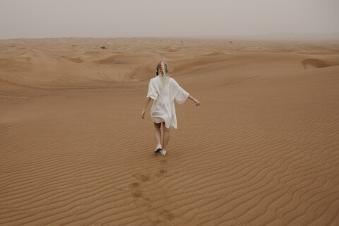 United Arab Emirates, Dubai, Lahbab Desert, woman walking in desert landscape stock photo