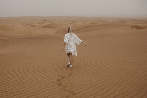 Vereinigte Arabische Emirate, Dubai, Wüste Lahbab, Frau geht in Wüstenlandschaft - LHPF00530