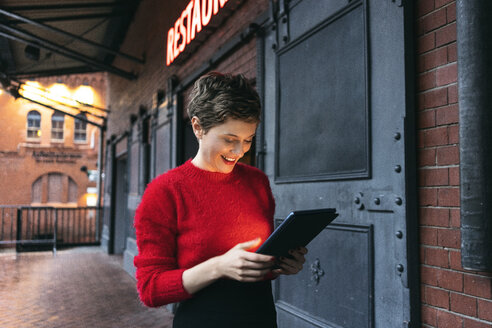 Deutschland, Berlin, lächelnde Restaurantleiterin mit digitalem Tablet im Freien - TAMF01275