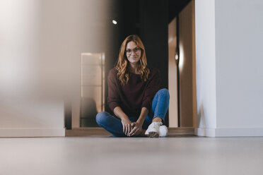 Portrait of smiling businesswoman sitting on the floor - GUSF01857