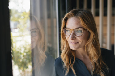 Portrait of smiling businesswoman looking out of window - GUSF01858