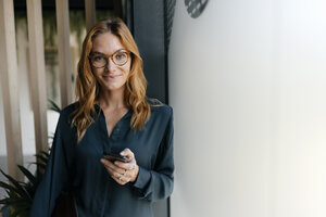 Porträt einer selbstbewussten Geschäftsfrau, die ein Mobiltelefon hält - GUSF01866