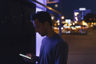 Junger Mann benutzt Handy in der Stadt bei Nacht - GUSF01867