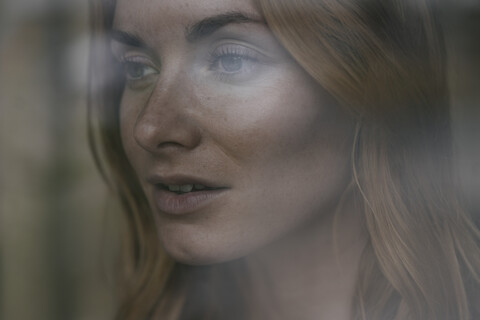 Close-up of young woman behind windowpane stock photo